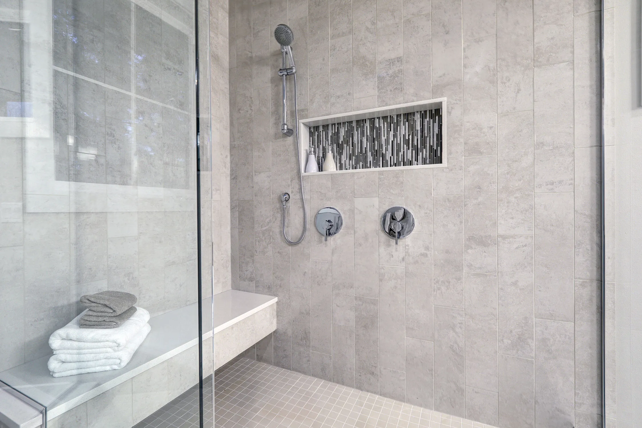 A bathroom with a glass shower door and a towel rack.